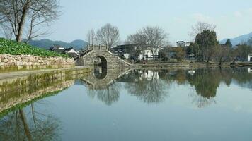 One old traditional Chinese village view with the old arched stone bridge and old wooden buildings in the Southern countryside of the China photo