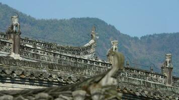 The ancient Chinese building roof view with the stone sculptures and black tiles roof located in the old Chinese village photo