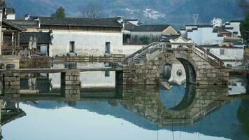 One old traditional Chinese village view with the old arched stone bridge and old wooden buildings in the Southern countryside of the China photo