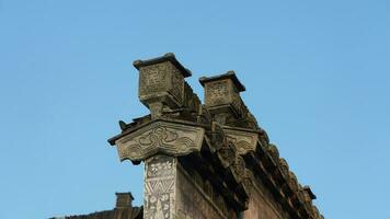 The ancient Chinese building roof view with the stone sculptures and black tiles roof located in the old Chinese village photo