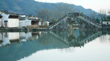 One old traditional Chinese village view with the old arched stone bridge and old wooden buildings in the Southern countryside of the China photo