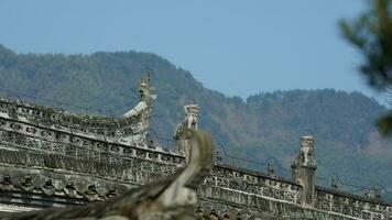 The ancient Chinese building roof view with the stone sculptures and black tiles roof located in the old Chinese village photo