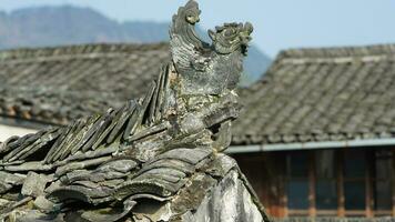 The ancient Chinese building roof view with the stone sculptures and black tiles roof located in the old Chinese village photo