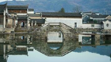 One old traditional Chinese village view with the old arched stone bridge and old wooden buildings in the Southern countryside of the China photo