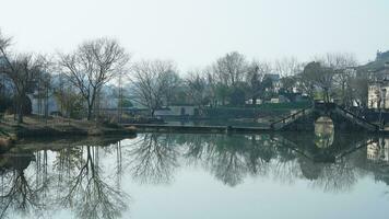 One old traditional Chinese village view with the old arched stone bridge and old wooden buildings in the Southern countryside of the China photo