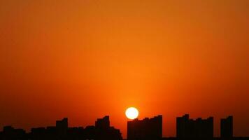 el hermosa puesta de sol ver con el edificios' silueta y naranja color cielo como antecedentes en el ciudad foto