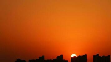 el hermosa puesta de sol ver con el edificios' silueta y naranja color cielo como antecedentes en el ciudad foto