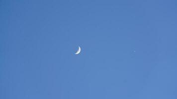 The blue sky view with the curve white moon in the sky in the day photo