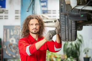 retrato de un joven coche mecánico en reparar cochera, técnico hombre trabajando en auto reparar comercio, coche reparar y mantenimiento conceptos foto