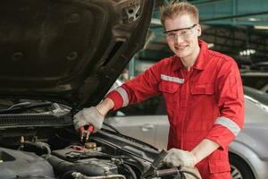 Auto mechanic working in garage, Technician man working in auto service, Technicians with charging cables for car battery, Car repair, and maintenance photo