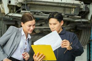 mecánico y joven mujer cliente hablando juntos a el reparar cochera, auto mecánico y hembra cliente en auto reparar comercio, coche reparar y mantenimiento conceptos foto