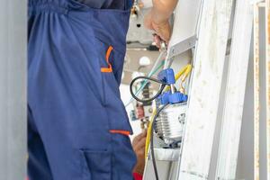 Technician man installing an air conditioning in a client house, Young repairman fixing air conditioner unit, Maintenance and repairing concepts photo