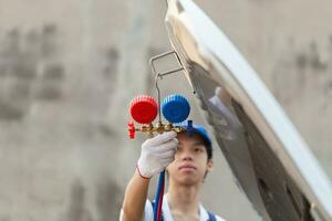 Technician check car air conditioning system refrigerant recharge, Repairman holding monitor tool to check and fixed car air conditioner system, Air Conditioning Repair photo