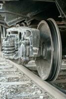 Wheel of a freight car standing on rails. Fixing the axle spring and shock absorber springs. Selective focus on the edge of the wheel. photo