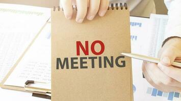 Text no meeting on brown paper notepad in businessman hands on the table with diagram. Business concept photo