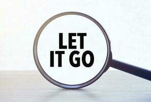 Magnifying glass with text let it go on wooden table. photo