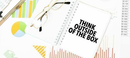 Text think outside of the box on white notepad, glasses, graphs and diagrams. photo