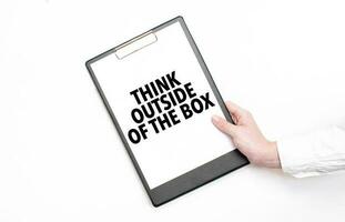 A businessman holds a folder with paper sheet with the text think outside of the box. Business concept. photo