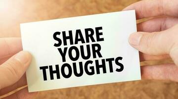 SHARE YOUR THOUGHTS word inscription on white card paper sheet in hands of a businessman. recap concept. red and white paper photo