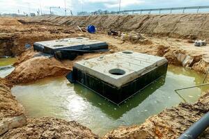 conectando un zanja desagüe a un hormigón agujero de hombre estructura a construcción sitio. hormigón pila en encofrado marco para construir aguas pluviales y subterráneo utilidades, bomba estaciones, alcantarillas tubería foto