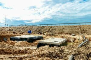 Connecting a trench drain to a concrete manhole structure at construction site. Concrete pile in formwork frame for construct stormwater and underground utilities, pump stations, sewers pipes photo