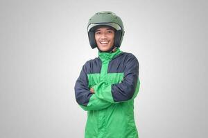 Portrait of Asian online taxi driver wearing green jacket and helmet, standing with crossed arms. Isolated image on white background photo