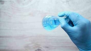 Hand of scientist holding lab glassware close up video