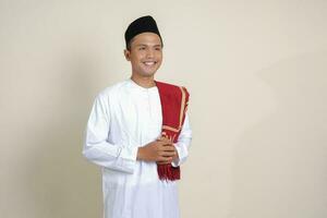 Portrait of attractive Asian muslim man in white shirt feeling confident, smiling and looking at camera. Isolated image on gray background photo