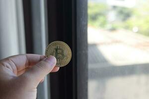 Close up of hand holding bitcoin against the window. Cryptocurrency trading concept photo