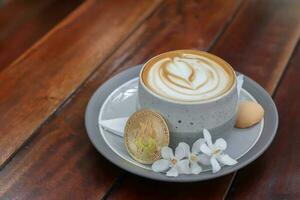 A cup of cappuccino with bitcoin on wooden table at cafe. Cryptocurrency trading concept photo