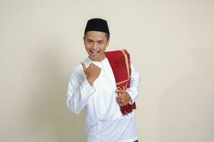 Portrait of attractive Asian muslim man in white shirt showing thumb up, good job hand gesture. Isolated image on gray background photo