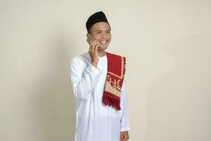 Portrait of attractive Asian muslim man in white shirt making phone call with explaining hand gesture. Isolated image on gray background photo