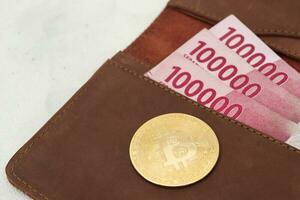 bitcoin con uno cien mil rupia billete de banco en cuero billetera. criptomoneda comercio concepto foto