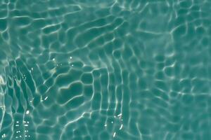 Green water with ripples on the surface. Defocus blurred transparent blue colored clear calm water surface texture with splashes and bubbles. Water waves with shining pattern texture background. photo