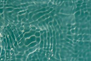 Green water with ripples on the surface. Defocus blurred transparent blue colored clear calm water surface texture with splashes and bubbles. Water waves with shining pattern texture background. photo