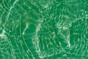 Green water with ripples on the surface. Defocus blurred transparent blue colored clear calm water surface texture with splashes and bubbles. Water waves with shining pattern texture background. photo