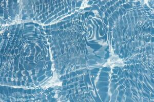 Blue water with ripples on the surface. Defocus blurred transparent blue colored clear calm water surface texture with splashes and bubbles. Water waves with shining pattern texture background. photo