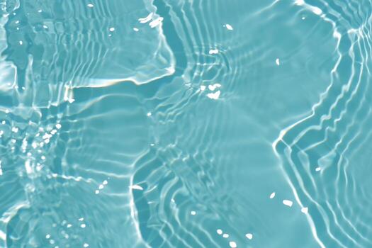 Blue water with ripples on the surface. Defocus blurred transparent blue colored clear calm water surface texture with splashes and bubbles. Water waves with shining pattern texture background. photo