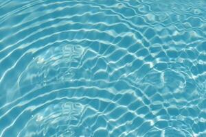 Blue water with ripples on the surface. Defocus blurred transparent blue colored clear calm water surface texture with splashes and bubbles. Water waves with shining pattern texture background. photo