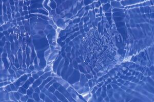 Blue water with ripples on the surface. Defocus blurred transparent blue colored clear calm water surface texture with splashes and bubbles. Water waves with shining pattern texture background. photo