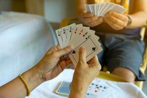 grupo de asiático amigos jugando tarjeta juegos para divertido en un Hostal durante su gratis hora mientras de viaje juntos.suave y selectivo enfocar. foto