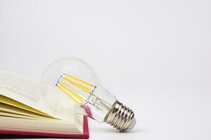 ligero bulbo brillante con libro en blanco antecedentes. concepto de conocimiento, sabiduría, nuevo ideas y creatividad. foto