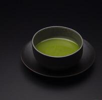 Matcha tea in the cup isolated on black background close up. Japanese tea ceremony concept. . photo