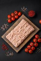 Fresh minced chicken with salt, spices and herbs on a wooden cutting board photo