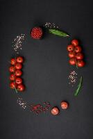 Empty black texture table, cherry tomatoes on a twig, spices, salt and herbs photo