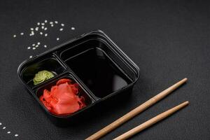 Pickled ginger, soy sauce and wasabi in portioned plastic containers photo