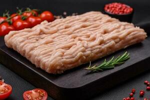 Fresh minced chicken with salt, spices and herbs on a wooden cutting board photo