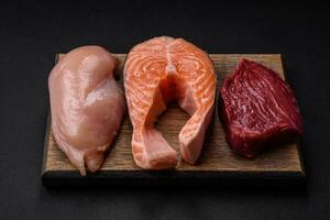 Chicken or turkey fillet, raw beef steak and salmon steak with spices and herbs photo