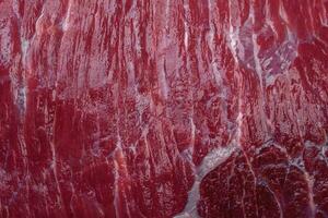 A piece of fresh raw beef with salt, spices and herbs on a wooden cutting board photo