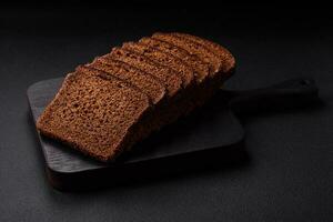 Delicious fresh brown bread with grains and seeds sliced on a wooden cutting board photo